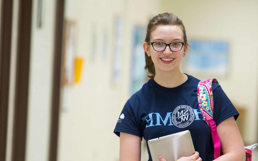 A student standing in the hall smiling.